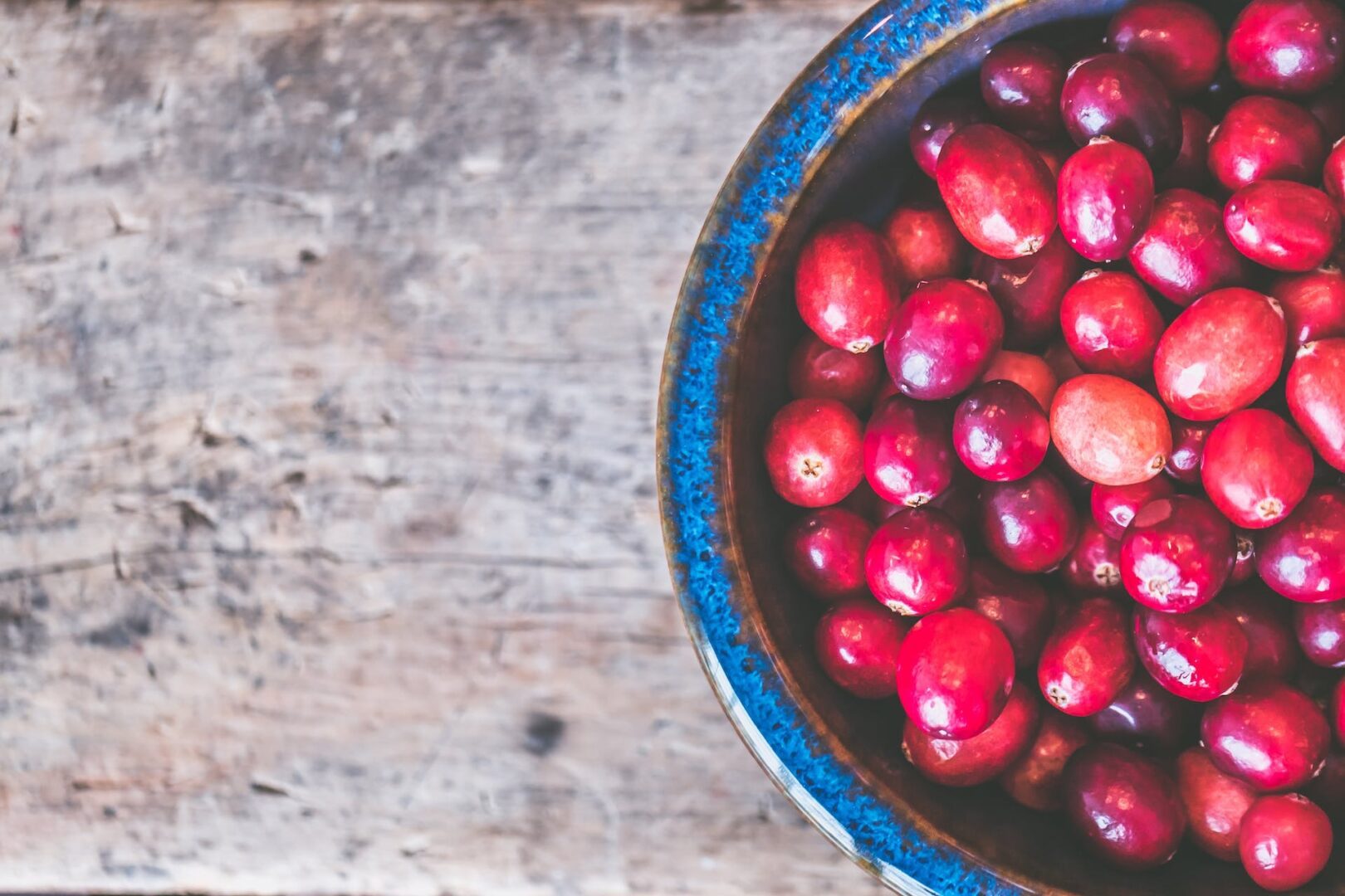 Cranberries in a bowl on a wooden table.