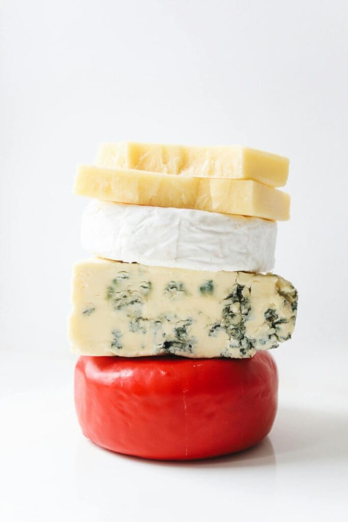 A stack of assorted cheese types on a white background, perfect for Mac and cheese recipes in the family lifestyle series.