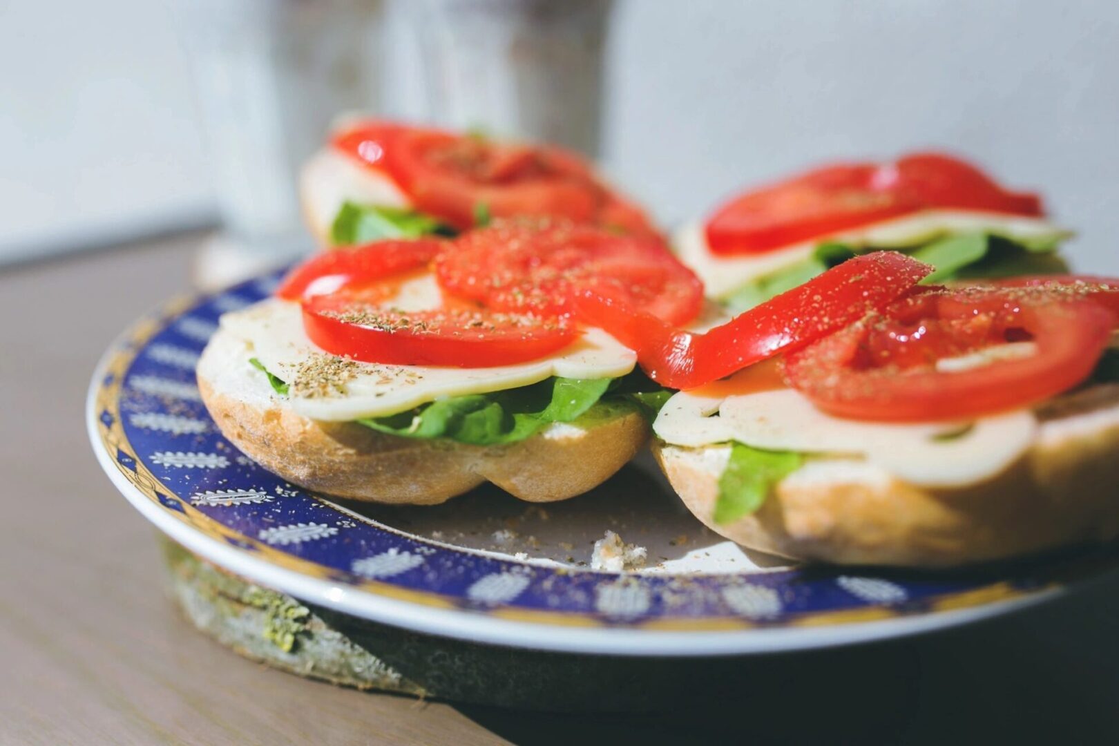A plate with a sandwich with tomatoes and cheese on it.