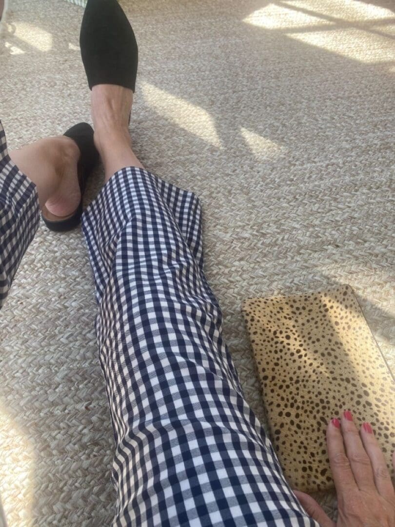 Person sitting with checkered pants, one foot in a black shoe, with a polka-dotted pillow nearby.