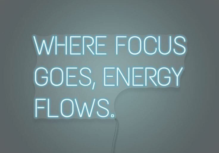 neon sign saying 'where focus goes energy flows'