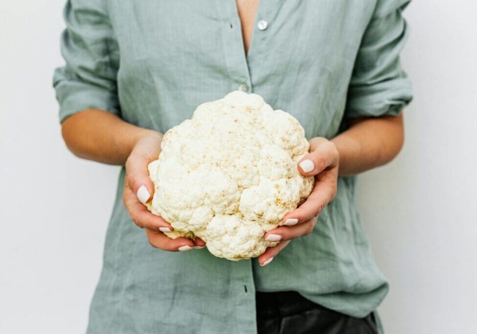  a woman holding a head of cauliflower